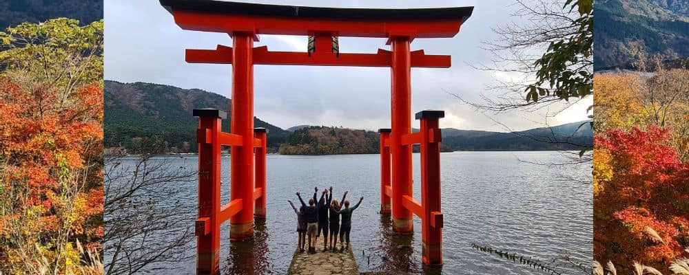 Trekking the Dream family stood under an iconic red Tori Gates by a lake. 