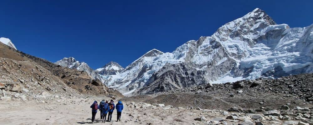 A family trekking on a dust path towards snow covered mountains. A bucket list destination.