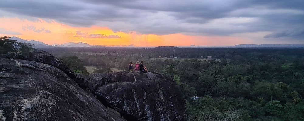 Kids on a rock watching sunset over looking rainforest. Sri Lanka is a hidden gem to add to any around the world itinerary .