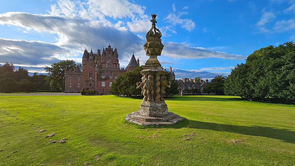 Multiple sundial on green grass in front of a Castle.