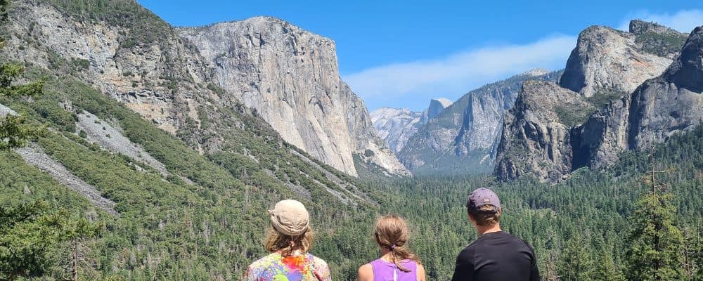 Kids looking out to forest and large iconic rocks in a national park while making memories on a family road trip.