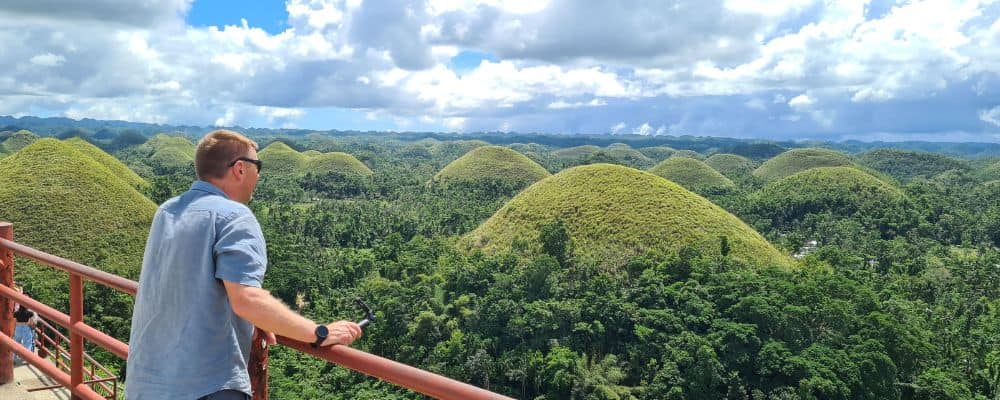 A man looking out to rolling green hills and rainforest in the Philippines. 