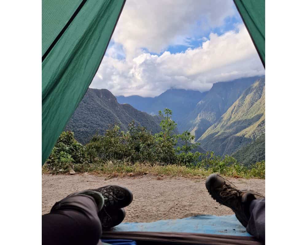 2 campers in a tent, opening onto a scenic mountain landscape in Peru