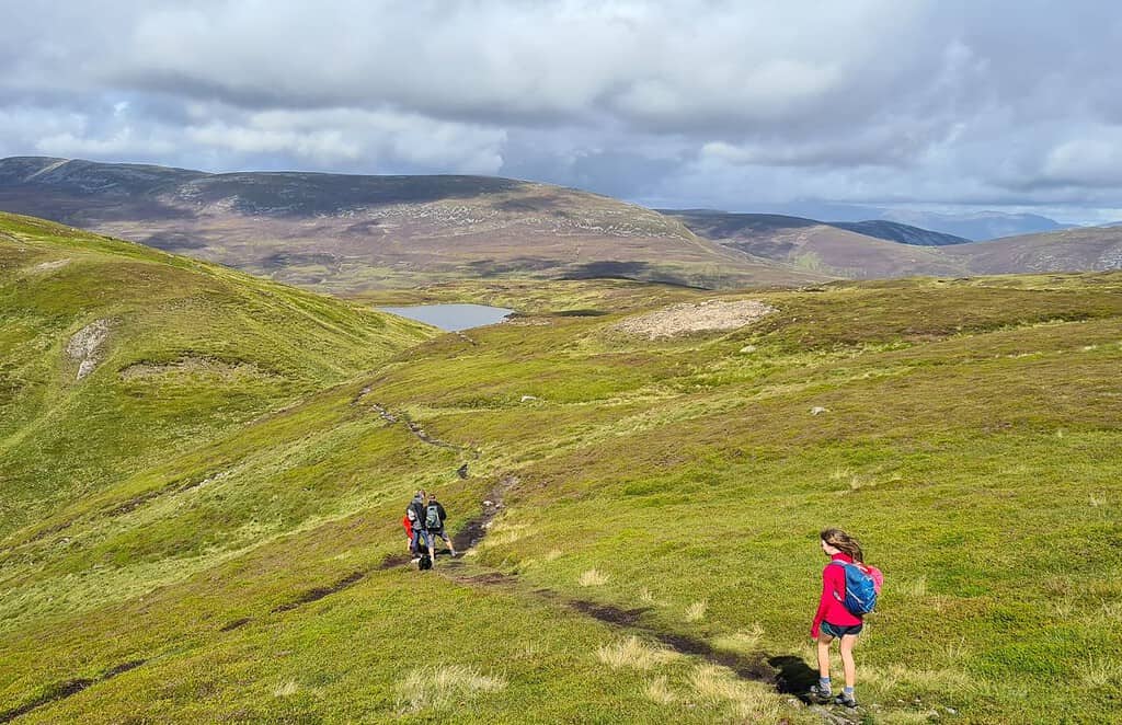 Family walking a path on grassy hills.