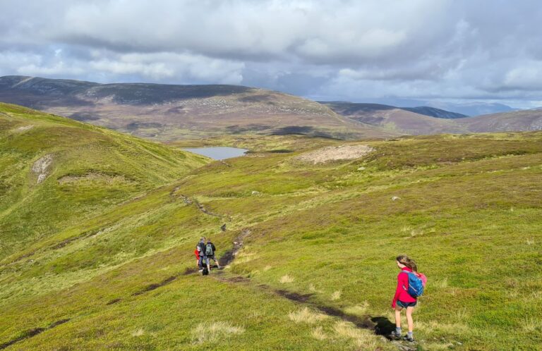 Family hiking a path on grassy hills.