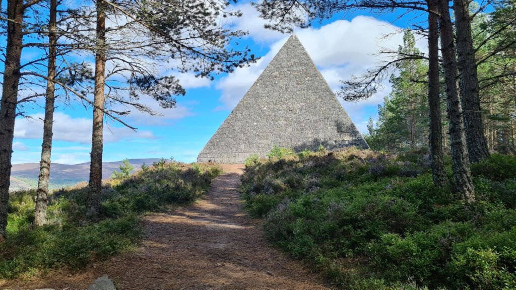 A wooded path in the Scottish highlands leading to a pyramid.