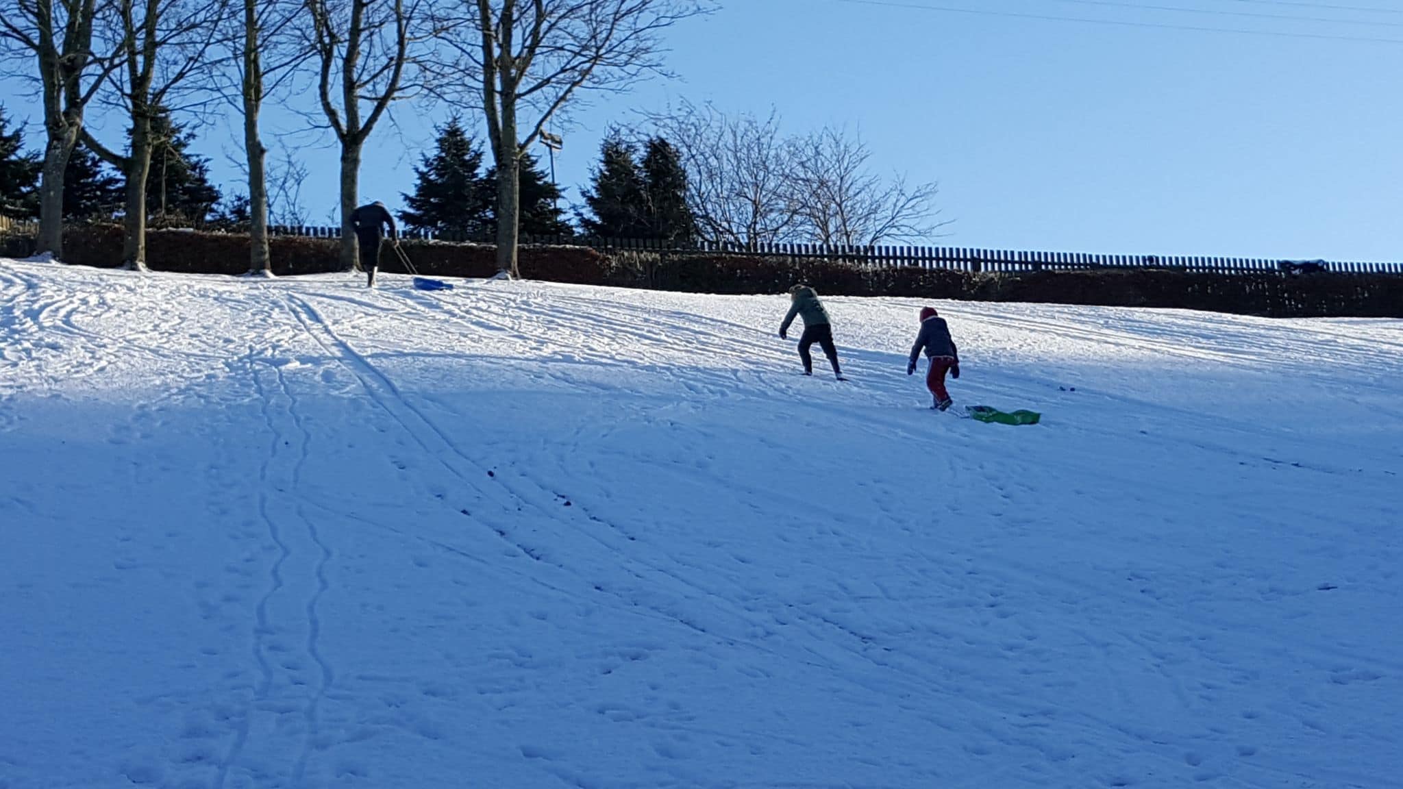 Family sledging on a snowy hill in Scotland.