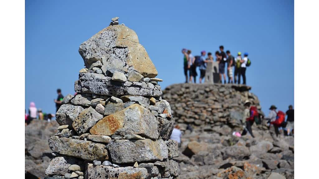 Hikers wating for a photo at the summit cairn on Ben Nevis.