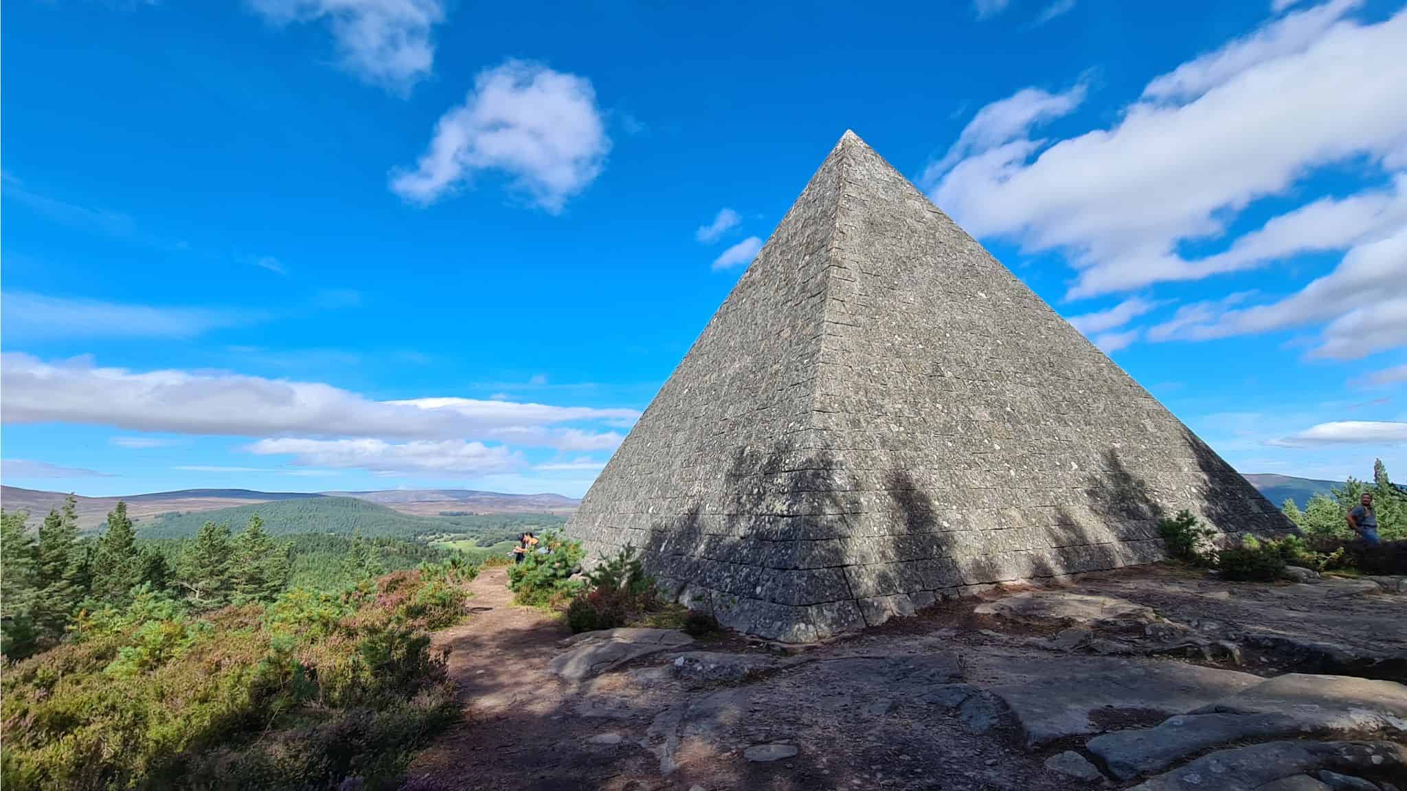 Granite pyramid overlooking forest with blue sky in Scotland