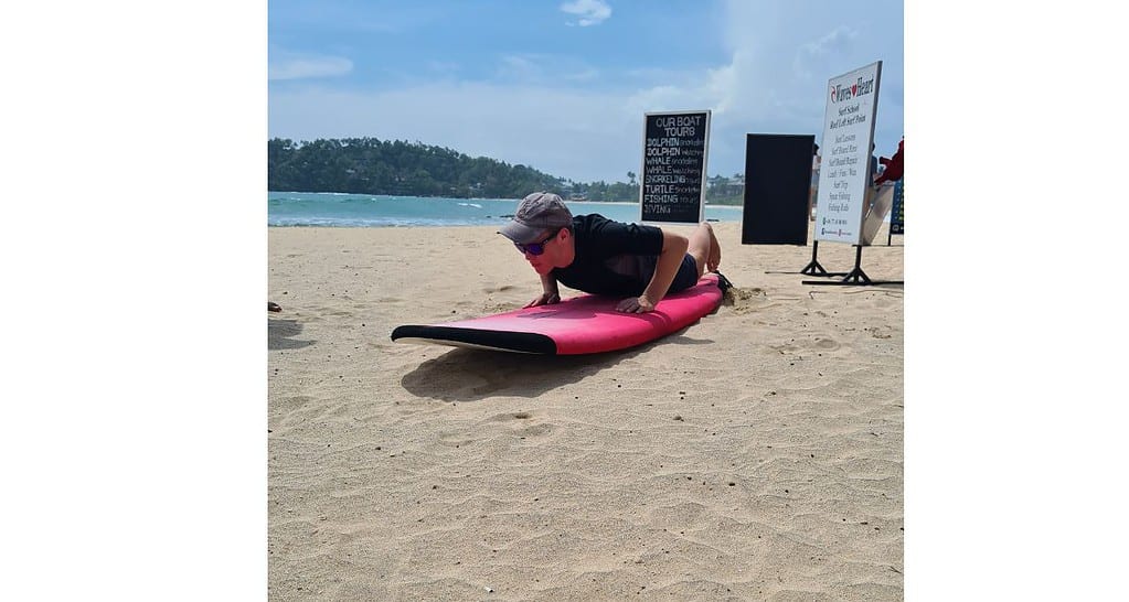 Boy practising drills on a surfboard on the beach in Mirissa.