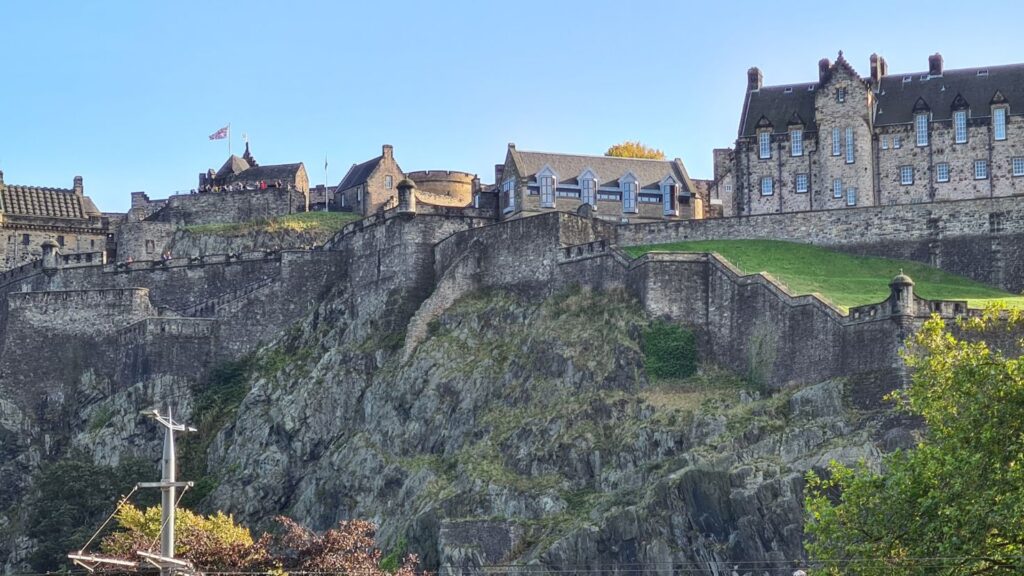 A stone castle on the top of a hill surrounded by trees in Edinburgh. 