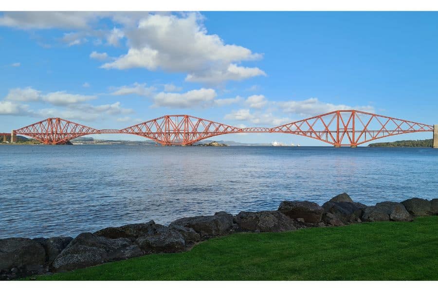 A view over a river to the red rail bridge in Edinburgh.