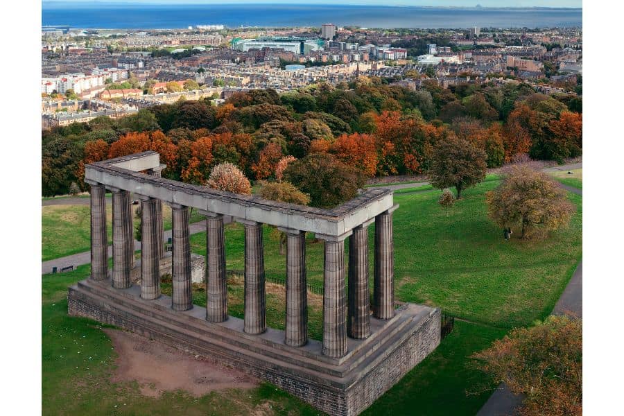 Historic monument over looking the city of Edinburgh surrounded by trees.