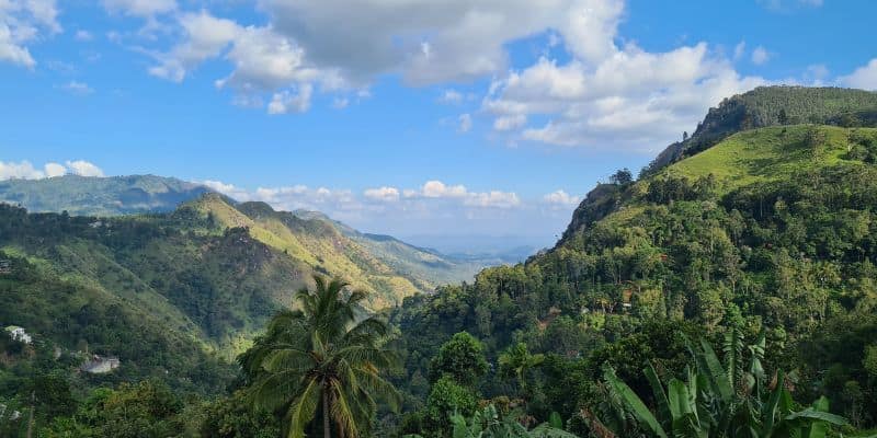 View through a vibrant green valley with blue sky and clouds on an ideal family road trip