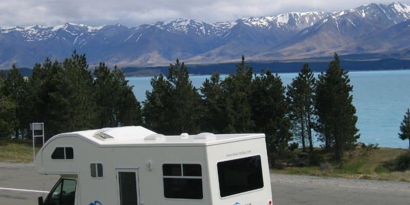 Family motorhome parked in an ideal location roadside of a lake with trees and Mountains. 