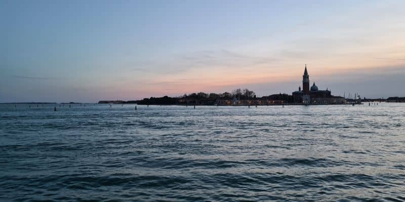 View over water of buildings as the sun sets in Venice