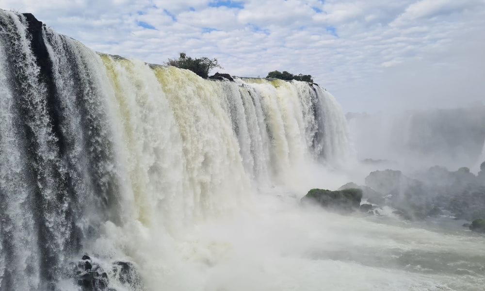 The best view of Powerful water pounding over falls with mist and rocks in Iguazu.
