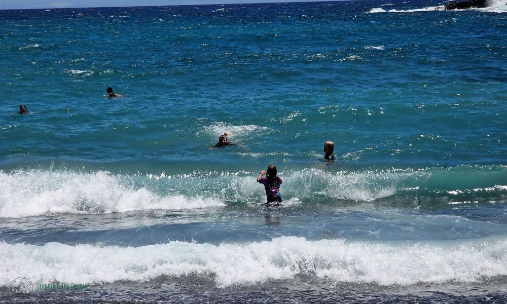 kids swimming in the ocean waves at Green Sand Beach Hawaii