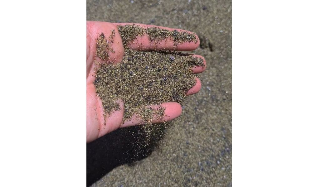 Green sand in a persons hand found on Papakolea beach one of only four green beaches in the world.