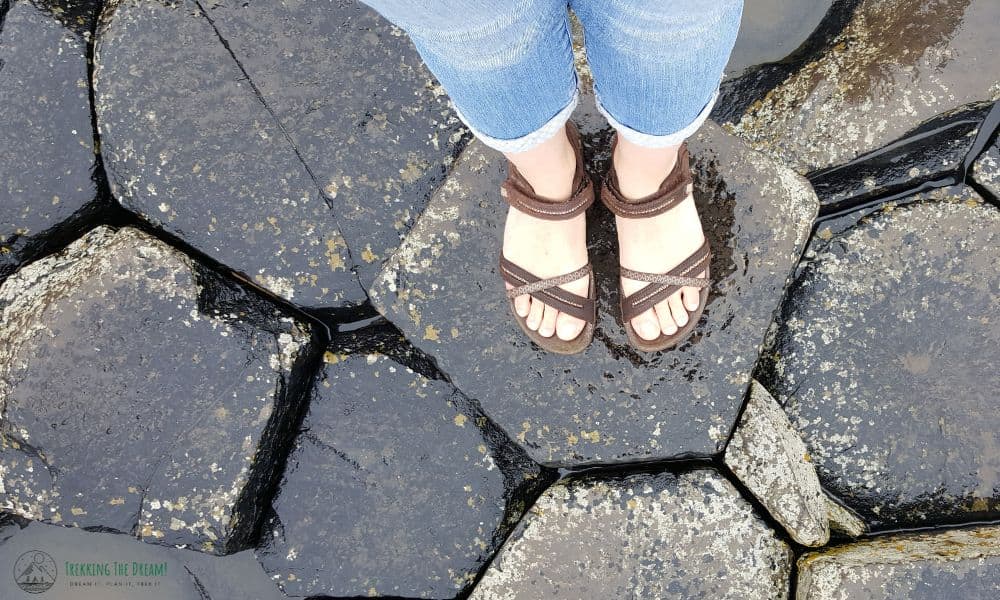 Person standing on wet rock formations at the Giants Causeway.