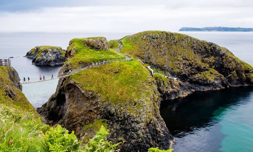 Large rock formations with a rope bridge that people are walking across