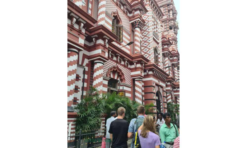 Red and white striped building with people walking away from in Colombo Sri Lanka