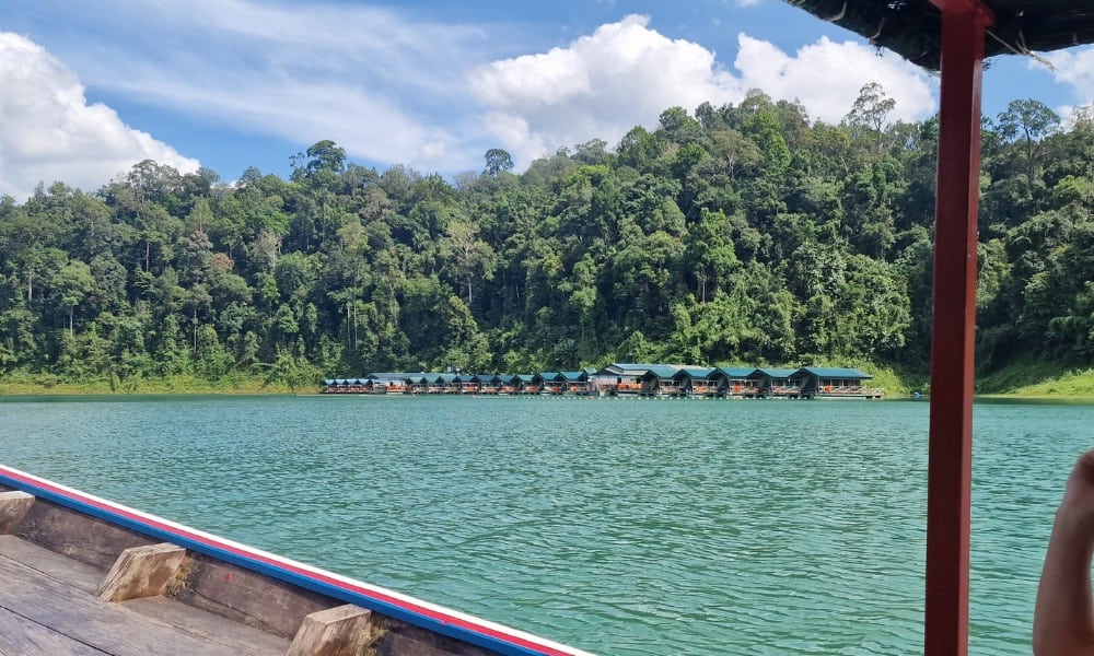 over water bungalows on a green lake surrounded by jungle in Thailand