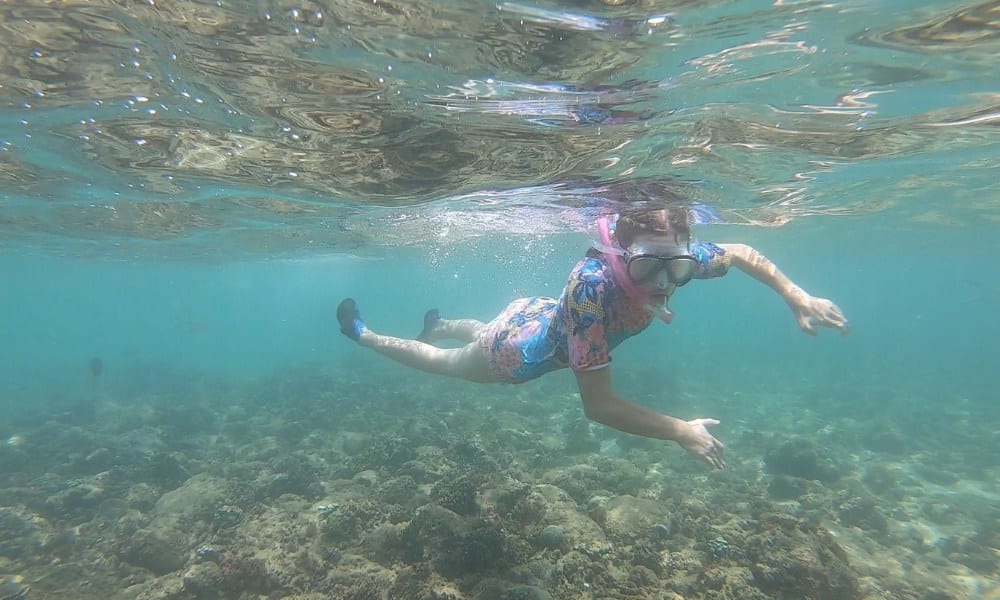 A kid snorkeling in shallow sea