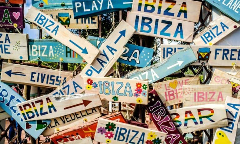 Many strips of wood with Ibiza painted on each in different colours attached to a gate. Confusion as to where Ibiza is located.