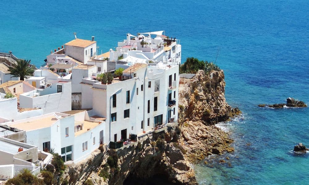 White houses on a cliff over looking blue ocean in Ibiza Town, Spain.