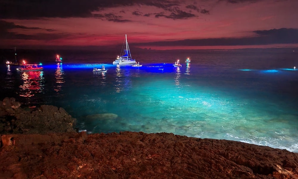 Spotlight on open water with boats and snorkellers with blue lights. A popular place for swimming with Manta Rays in Hawaii.