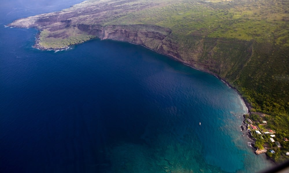 Kealakekua Bay birds eye view of a body of water and cliff surrounding it. This is some of the best snorkeling on Big Island Hawaii