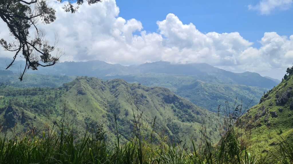 Green jagged hills with blue sky and white clouds. A scenic view point hiking to Ella Rock, Sri Lanka