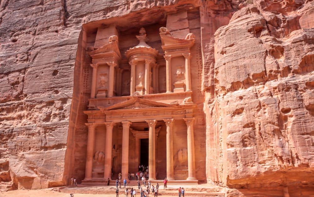 large carved stone building in a desert. Lots of people visit this wonder of the world 