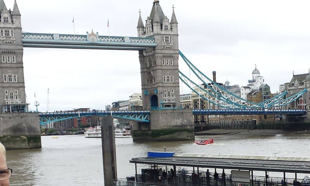 A road bridge with two castle like towers over a river in London, known as Tower Bridge.