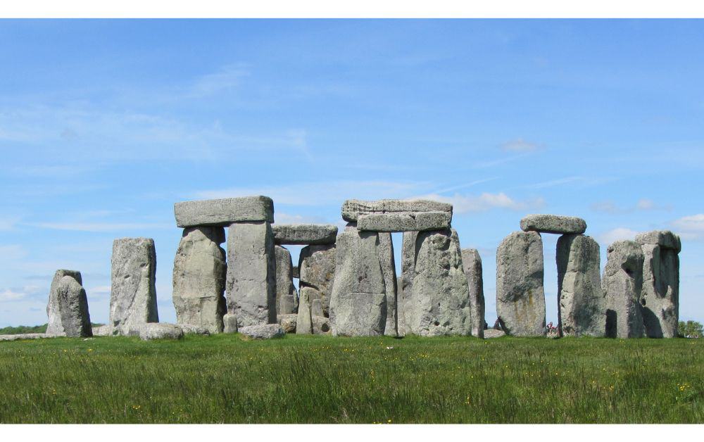 large standing stones in a circle on grass. Stonehenge is a top places to visit in the UK.