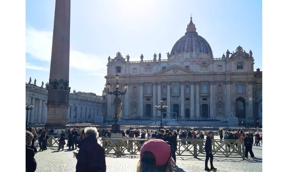 A grand building with a dome on top surrounded by fences and people. Vatican city is a unique reason to visit Italy for 3 days.