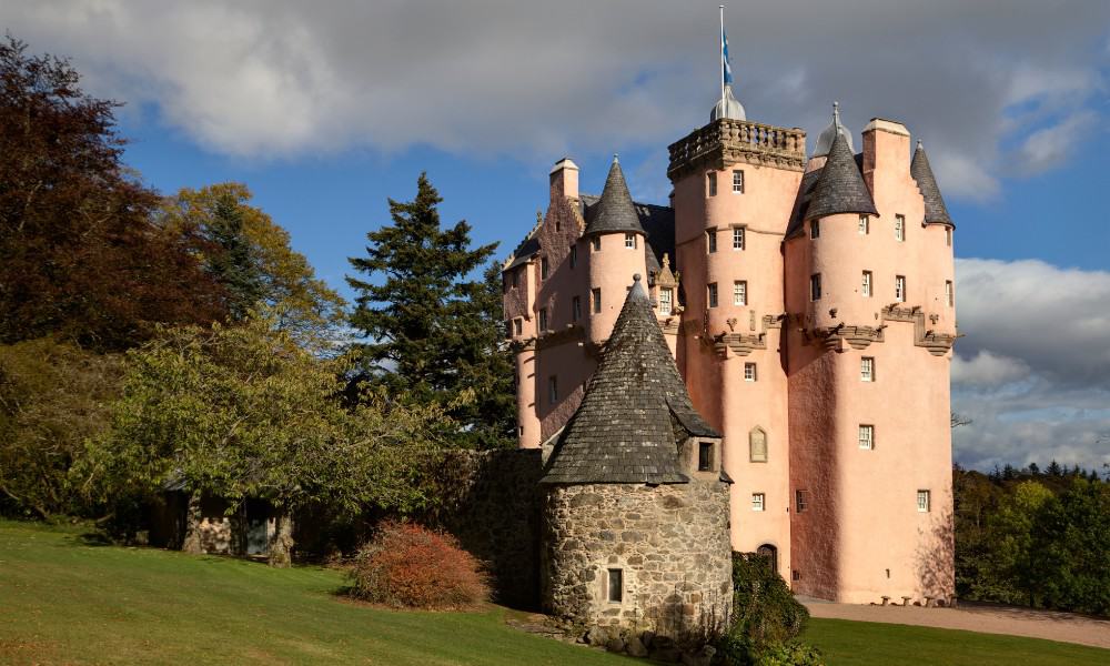 A pink Disney fairytale castle with turrets surrounded by woodland in Scotland