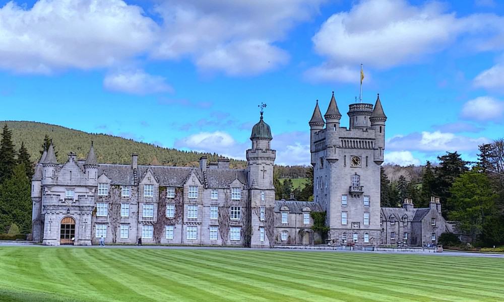 Large royal castle surrounded by grass and hills in Scotland where royals stay in the summer. 