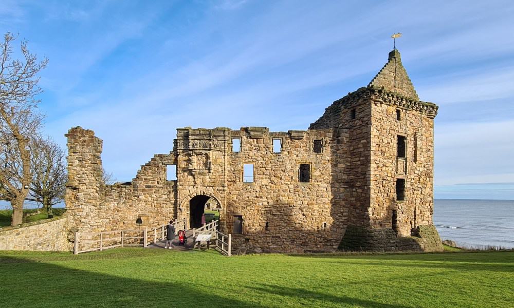 large partical ruined castle on green grass overlooking the sea. St Andrews has a castle in Scotland worth visiting.