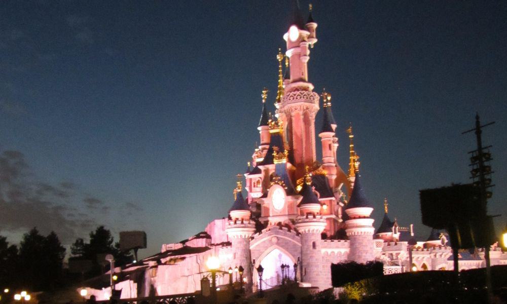 Pink fairy tale castle illuminated against a night sky at Disneyland Paris  