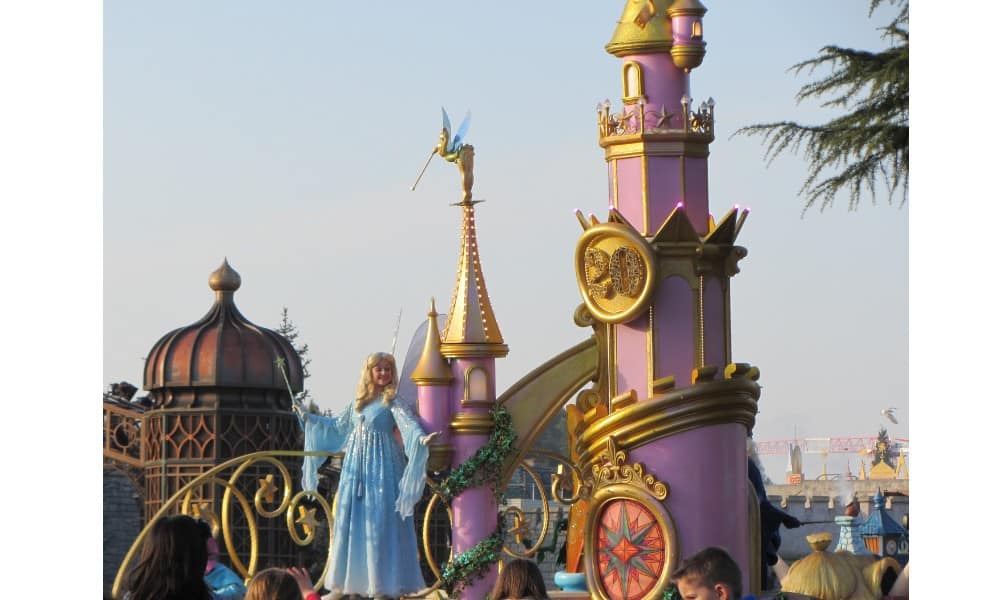 Purple and gold fairyland castle on parade with a blue princess. An iconic site at Disneyland.