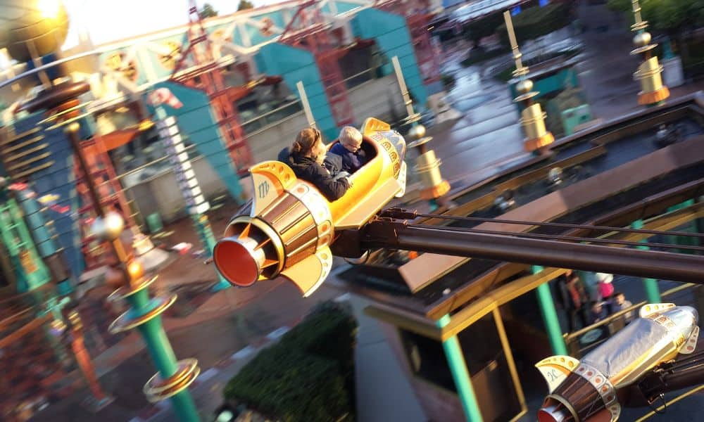 blurred background with Trekking The Dream family riding a yellow rocket ride at Disneyland Paris.