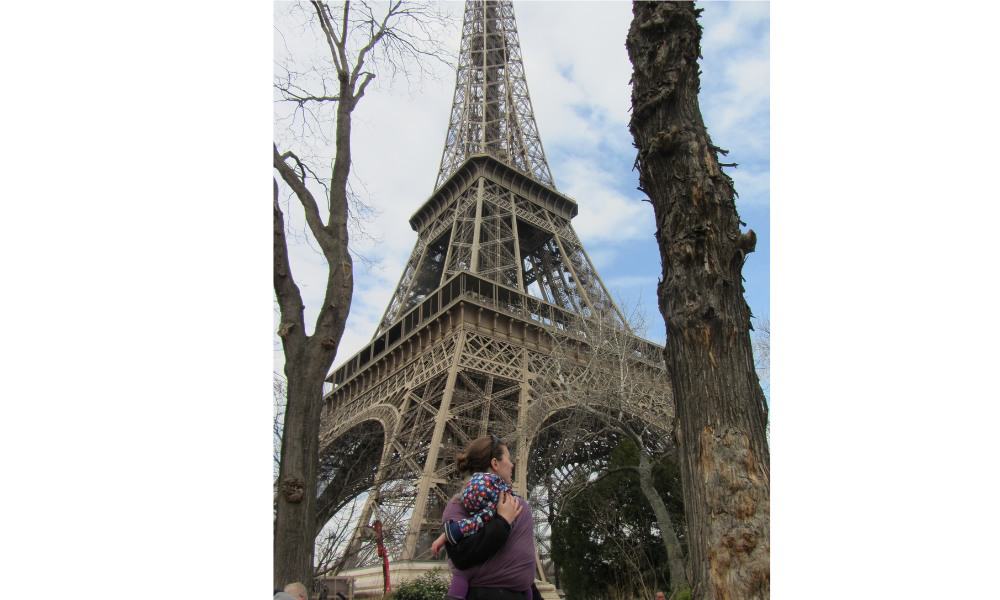 Trekking The Dream Family admiring a large metal structure. The Eiffel Tower is a popular attraction in Paris.