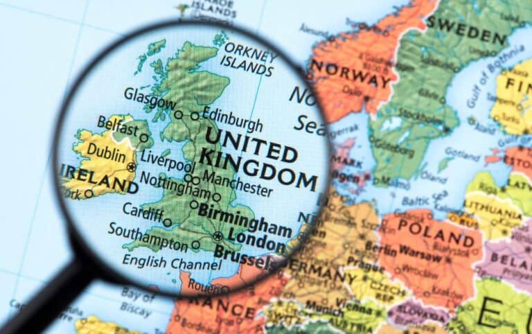 Magnifying glass enlarging UK on a world map. Used when deciding the best places to visit in the UK.