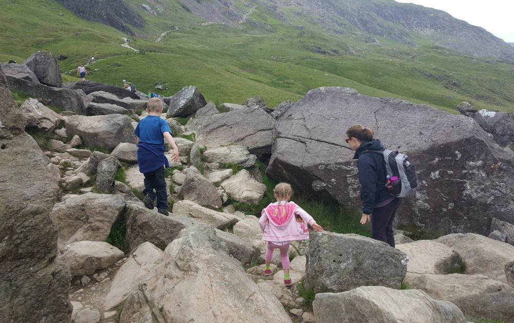 Trekking the Dream family climbing over large boulders after hiking to the summit. 