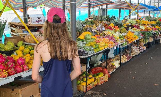 A kid looking at colourful fruit at a market.