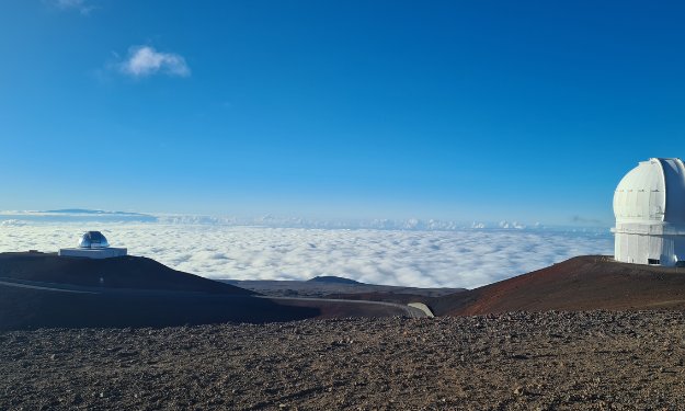 top of the volcano view over low lying clouds and blue sky on Mauna Kea Hawaii.