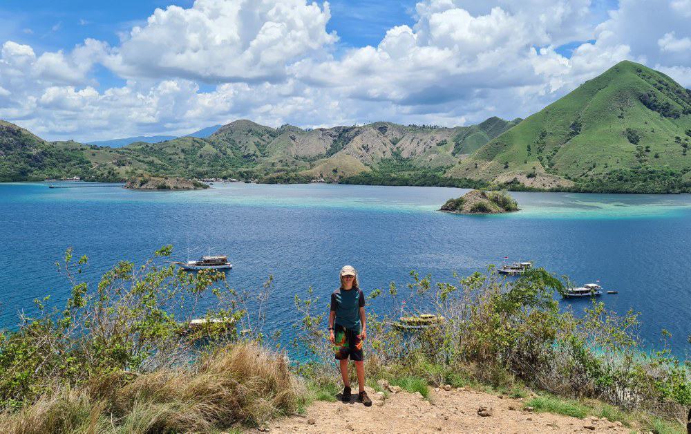 A kid stood on a scenic viewpoint overlooking sea and pointy hills on a Komodo boat tour