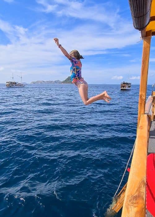 Kid jumping into the sea from a boat - an activity on Trekking the Dreams boat trip to Komodo Island.